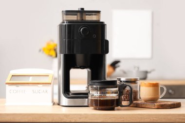 Modern kahve makinesi, fasulye ve bir bardak espresso mutfaktaki ahşap masada.