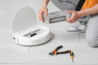 Modern robot elektrik süpürgesini tamir eden adam, yakın plan.