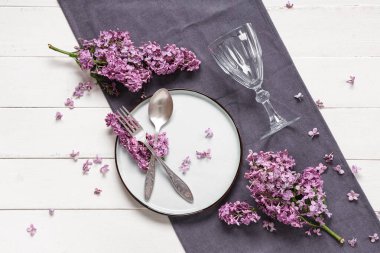 Beyaz ahşap arka planda leylak çiçekleri olan güzel bir masa.