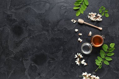 Akasya çiçekli tatlı bal kavanozu ve siyah arkaplanlı dipper.