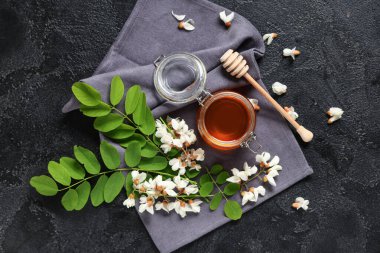 Akasya çiçekli tatlı bal kavanozu ve siyah arkaplanlı dipper.