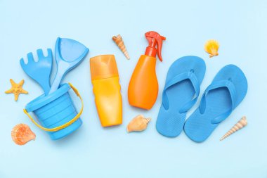 Mavi arka plandaki çocuklar için güneş kremi ve plaj aksesuarlarıyla harika bir kompozisyon.