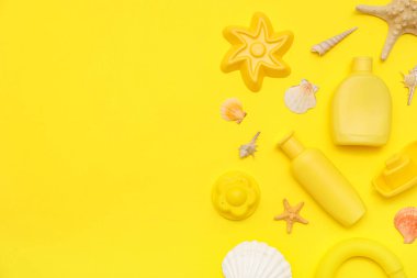 Sarı arka plandaki çocuklar için güneş kremi ve plaj aksesuarlarıyla güzel bir kompozisyon
