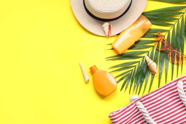 Plaj aksesuarları ve sarı arka planda güneş kremi olan güzel bir kompozisyon.