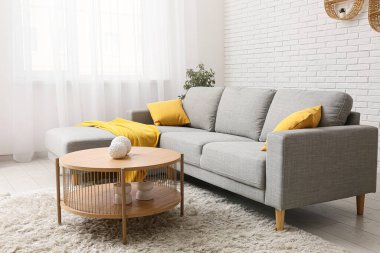 Gri kanepeli, sehpalı ve yastıklı oturma odasının içinde.