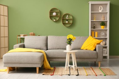 Şık oturma odasının içinde rahat bir kanepe, sehpasında çiçekler ve yastık olan vazo.