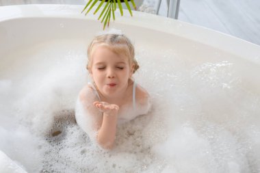 Köpüklü, köpüklü, banyoda banyo yapan tatlı küçük kız.