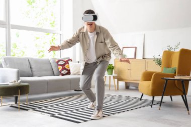 Young man using VR glasses at home