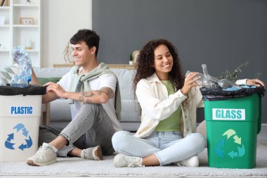 Evlerinde çöp kutularını düzenleyen genç bir çift. Geri dönüşüm kavramı