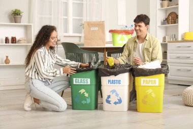 Mutfaktaki çöpleri düzenleyen çöp konteynırları olan genç bir çift. Geri dönüşüm kavramı