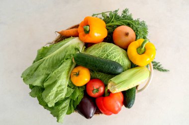 Beyaz arka planda farklı taze sebzelerle dolu bir sepet.