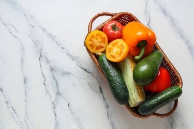 Beyaz arka planda farklı taze sebzelerle dolu bir sepet.