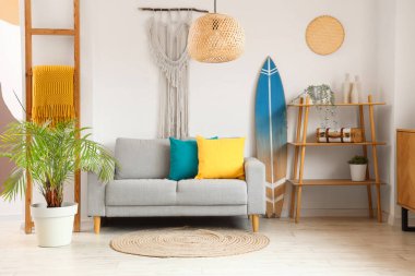 Gri kanepeli, raf üniteli ve sörf tahtalı bir oturma odası.