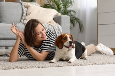 Genç bir kadın yerde tatlı bir tazı köpeğiyle yatıyor.