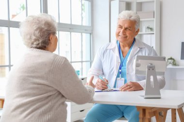 Klinikte yaşlı bir kadınla çalışan olgun bir doktor.