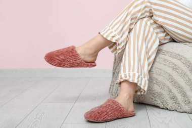 Evde yumuşak terlikli genç bir kadın var.