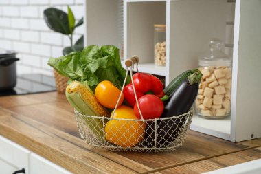 Ahşap mutfak tezgahında farklı taze sebzelerin olduğu sepet, yakın plan.