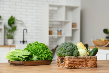 Tahta mutfak tezgahında farklı taze sebzelerle dolu bir sepet.