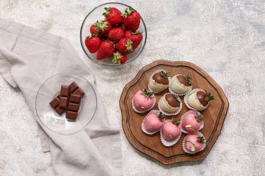 Çikolata kaplı çilekli ahşap tahta tahta tahta ve gri arka planda cam bir kase taze çilek.