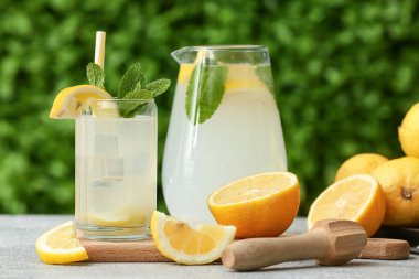 Dışarıdaki gri masada naneli taze limonata ve cam sürahi.