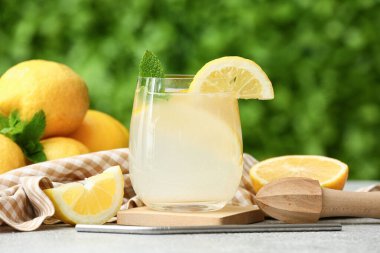 Dışarıdaki gri masada naneli ve meyve sıkacağıyla bir bardak taze limonata.