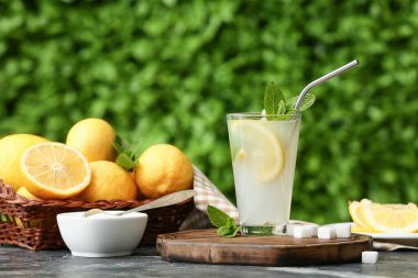 Dışarıdaki siyah masada naneli ve şekerli bir bardak taze limonata.