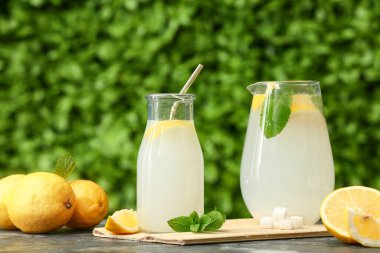 Bir şişe taze limonata ve açık havada siyah masada nane şekeri.