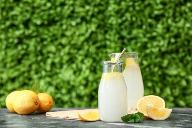 Bir şişe taze limonata ve açık havada siyah masada nane şekeri.