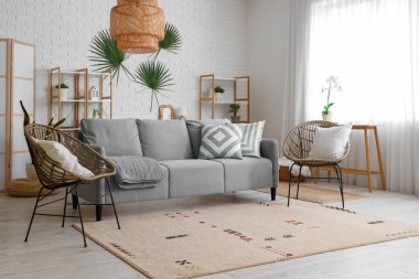 Oturma odasının içinde kanepe, koltuk ve raf üniteleri var.