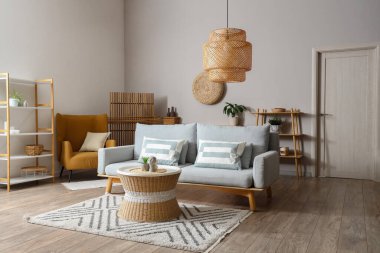 Oturma odasının içinde kanepe, rattan masa ve raf üniteleri var.