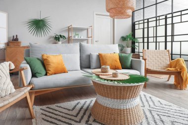 Oturma odasının içinde kanepe, koltuk ve rattan masa var.