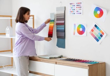 Ofisinde kumaş örnekleri olan kadın iç mimar.