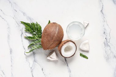 Taze hindistan cevizleri, bir bardak su ve beyaz arka planda yapraklar.