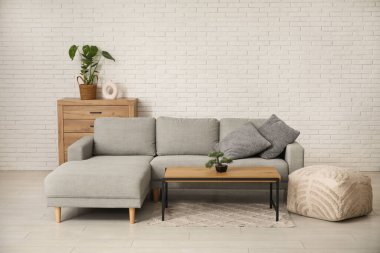 Oturma odasının içinde yastıklı, puf ve sehpalı rahat bir kanepe.