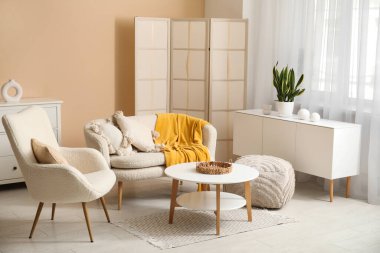 Ekose ve yastıklı kanepe, puf, sehpa ve oturma odasında koltuk.