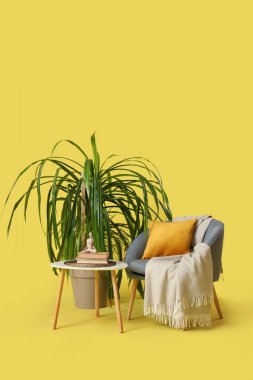 Masası ve sarı arka planı olan bir palmiye ağacı.