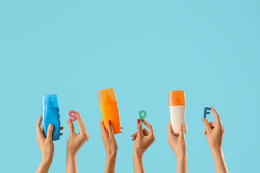 Güneş kremi ve harfler mavi arka planda kadın ellerinde SPF