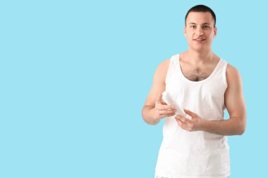 Mavi arka planda deodorantı olan yakışıklı bir genç.