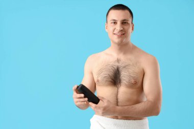 Mavi arka planda deodorantı olan yakışıklı bir genç.