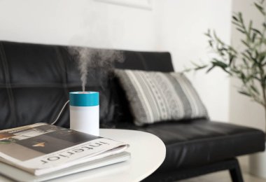 Oturma odasındaki dergilerle hava nemlendirici, yakın plan.