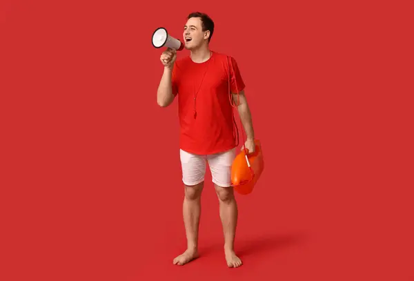 Stock image Male lifeguard with rescue tube buoy and megaphone on red background