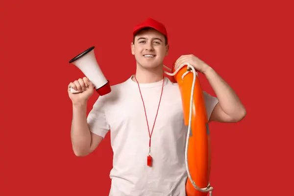 stock image Portrait of male lifeguard with ring buoy and megaphone on red background