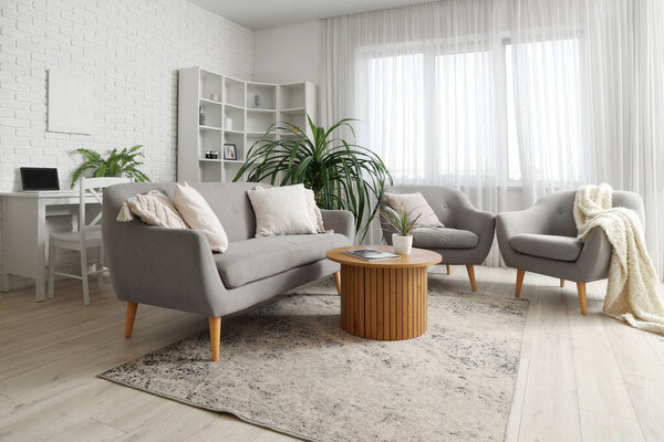 Comfortable sofa and armchairs with plaid in living room