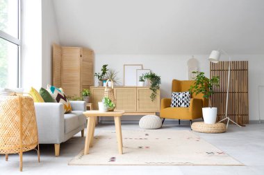 Gri kanepesi, koltuğu ve çekmeceleri olan aydınlık oturma odasının içi.