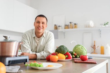 Mutfaktaki masada taze sebzeli genç adam.