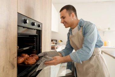 Genç adam mutfaktan çöreklerle tepsi alıyor.