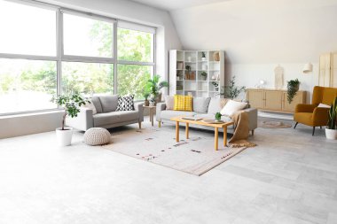 Gri koltukları, masası ve büyük penceresi olan oturma odasının içinde.