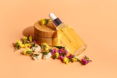 Turuncu arka planda güzel çiçekli şişe ve kozmetik ürünleri.