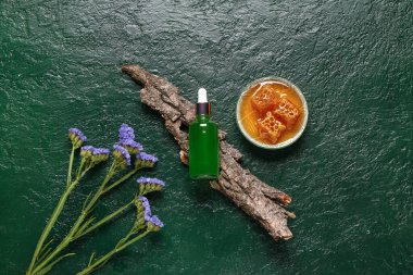 Güzel çiçekli bir şişe kozmetik yağı ve yeşil arka planda bal.