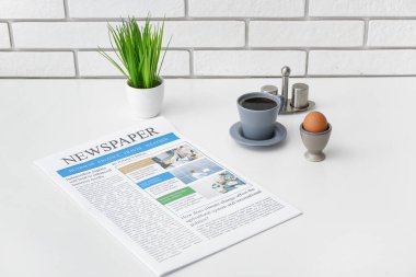 Beyaz masadaki kahve ve yumurtalı gazete.
